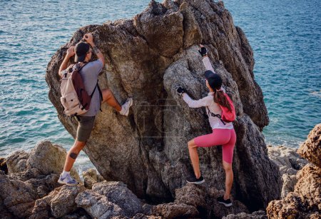 Photo for Happy young couple climbs to the top in the mountains near the ocean. - Royalty Free Image