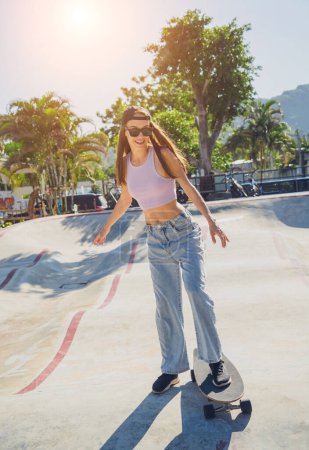 Téléchargez les photos : Joyeux jeune femme avec skateboard profiter du longboard au skatepark. - en image libre de droit
