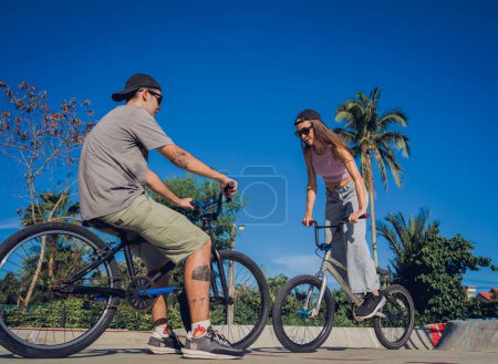 Foto de Jóvenes feliz pareja disfrutar de BMX montar en el skatepark. - Imagen libre de derechos