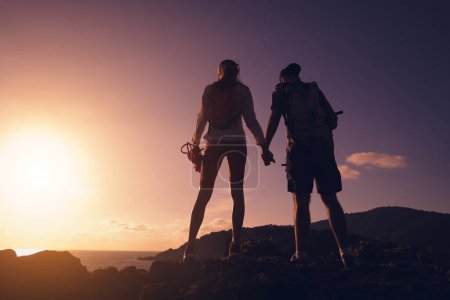 Téléchargez les photos : Heureux jeune couple monte au sommet dans les montagnes près de l'océan. - en image libre de droit