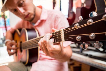 Foto de Joven músico probando guitarra clásica en una tienda de guitarra. - Imagen libre de derechos