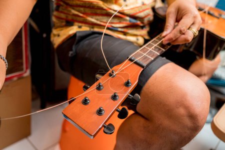Téléchargez les photos : Jeune musicien changeant de cordes sur une guitare classique dans un magasin de guitare. - en image libre de droit