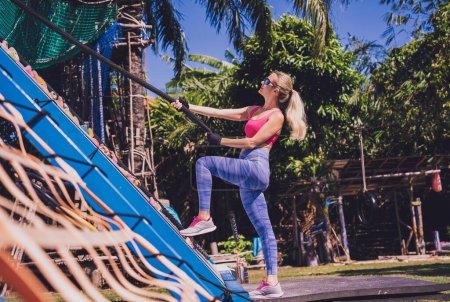 Photo for Athletic young woman working out and climbing a ropes at the rope training camp - Royalty Free Image