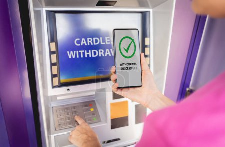 Photo for Young woman using the smart phone for cardless withdrawing the cash near the ATM. - Royalty Free Image