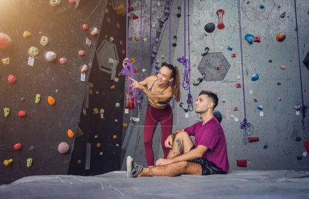 Foto de Un fuerte par de escaladores contra una pared artificial con pintorescos agarres y cuerdas - Imagen libre de derechos