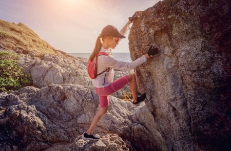 Foto de Mujer joven sube a la cima en las montañas cerca del océano. - Imagen libre de derechos