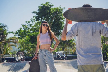 Foto de Joven pareja feliz con monopatines disfrutan del longboard en el skatepark. - Imagen libre de derechos