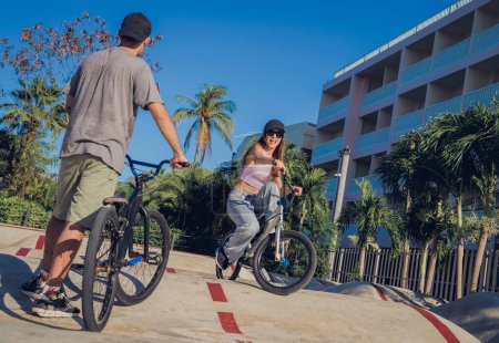 Téléchargez les photos : Jeune couple heureux profiter BMX équitation au skatepark. - en image libre de droit