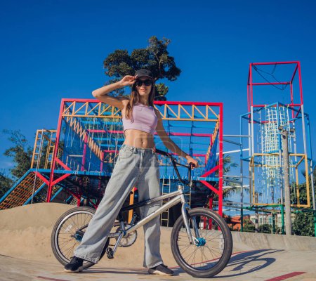 Téléchargez les photos : Joyeux jeune femme profiter BMX équitation au skatepark. - en image libre de droit