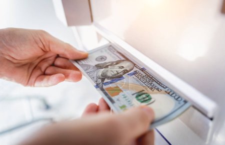 Téléchargez les photos : Jeune femme tenant de l'argent dans ses mains après avoir retiré l'argent au guichet automatique. - en image libre de droit