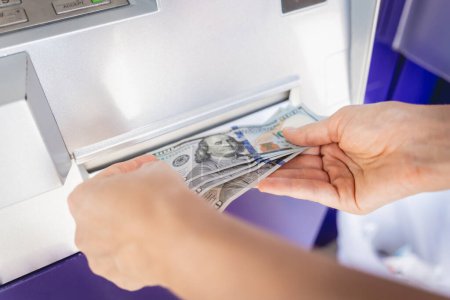 Foto de Mujer joven sosteniendo el dinero en sus manos después de retirar el dinero en efectivo en el cajero automático. - Imagen libre de derechos