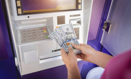 Foto de Mujer joven sosteniendo el dinero en sus manos después de retirar el dinero en efectivo en el cajero automático. - Imagen libre de derechos