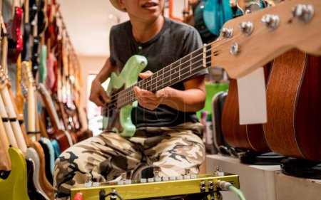 Foto de Joven músico probando bajo guitarra en una tienda de guitarra. - Imagen libre de derechos