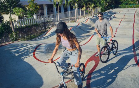 Foto de Jóvenes feliz pareja disfrutar de BMX montar en el skatepark. - Imagen libre de derechos
