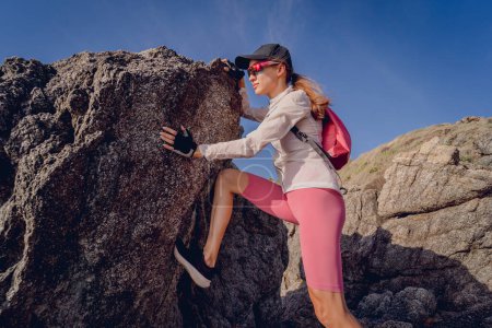 Téléchargez les photos : Jeune femme monte au sommet dans les montagnes près de l'océan. - en image libre de droit
