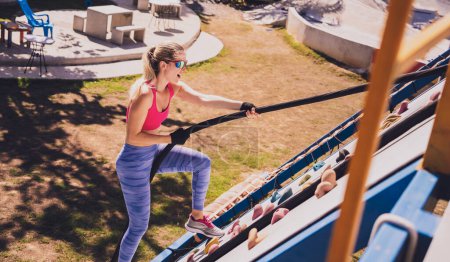 Foto de Mujer joven atlética haciendo ejercicio y trepando una cuerda en el campamento de entrenamiento de cuerdas - Imagen libre de derechos