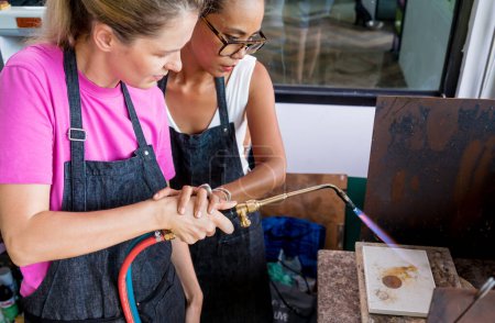 Téléchargez les photos : Professeur bijoutier et étudiant utilisant un brûleur en atelier. - en image libre de droit