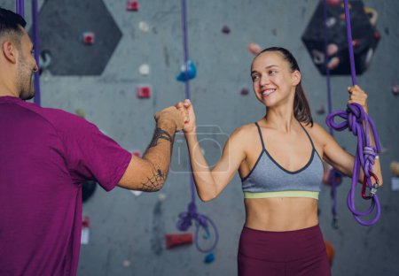 Téléchargez les photos : Un couple fort d'alpinistes contre un mur artificiel avec des poignées et des cordes colorées - en image libre de droit