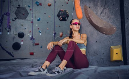 Téléchargez les photos : Une grimpeuse forte contre un mur artificiel avec des poignées et des cordes colorées - en image libre de droit