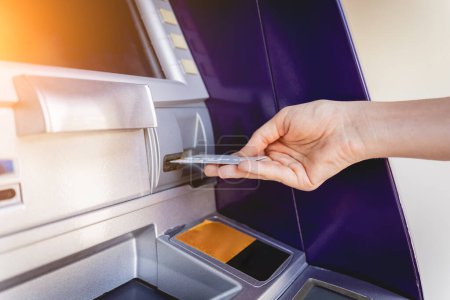 Photo for Young woman using the card for withdrawing the cash in the ATM. - Royalty Free Image