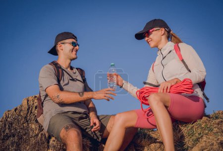 Téléchargez les photos : Heureux jeune couple se détendre après les montées au sommet des montagnes près de l'océan. - en image libre de droit