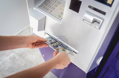 Téléchargez les photos : Jeune femme tenant de l'argent dans ses mains après avoir retiré l'argent au guichet automatique. - en image libre de droit