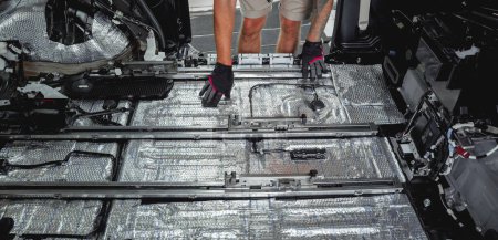 Téléchargez les photos : Tunning travailleur de service installer le matériel d'insonorisation à l'intérieur de la voiture intérieure. - en image libre de droit