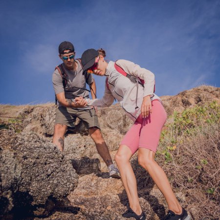 Foto de Feliz pareja joven sube a la cima en las montañas cerca del océano. - Imagen libre de derechos