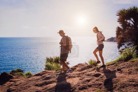 Photo for Young couple climbs to the top in the mountains near the ocean. - Royalty Free Image