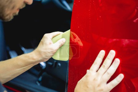 Photo for The process of installing protective film on the new red car - Royalty Free Image