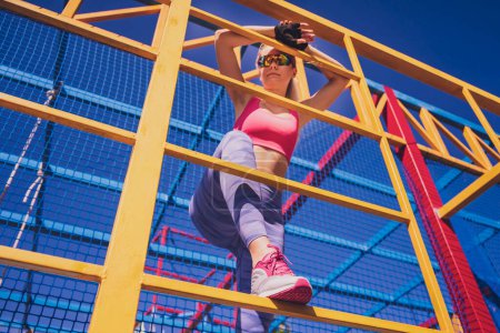 Téléchargez les photos : Jeune femme sportive faisant de l'exercice et de l'escalade au camp d'entraînement - en image libre de droit