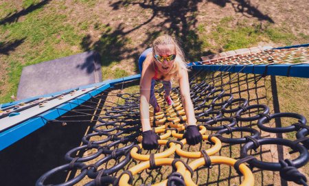 Téléchargez les photos : Jeune femme athlétique travaillant et escaladant des cordes au camp d'entraînement à la corde - en image libre de droit