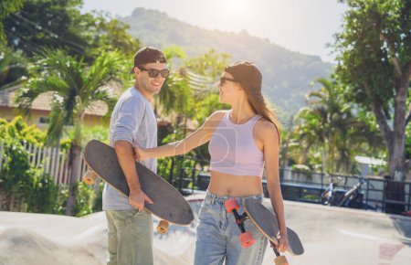 Photo for Young happy couple with skateboards enjoy longboarding at the skatepark. - Royalty Free Image