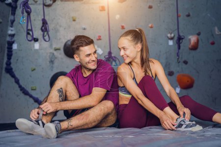Photo for A strong couple of climbers against an artificial wall with colorful grips and ropes - Royalty Free Image