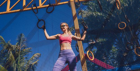 Téléchargez les photos : Jeune femme sportive faisant de l'exercice avec des anneaux de gymnastique dans un camp d'entraînement. - en image libre de droit