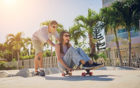 Téléchargez les photos : Jeune couple heureux avec planches à roulettes profiter du longboard au skatepark. - en image libre de droit