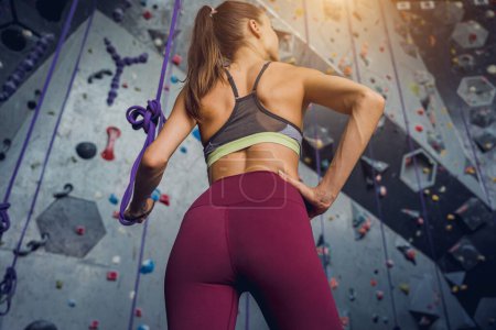 Foto de Una fuerte escaladora contra una pared artificial con pintorescos agarres y cuerdas - Imagen libre de derechos