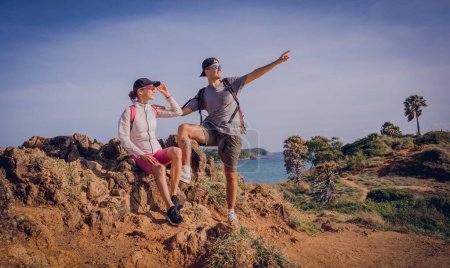 Photo for Happy young couple climbs to the top in the mountains near the ocean. - Royalty Free Image