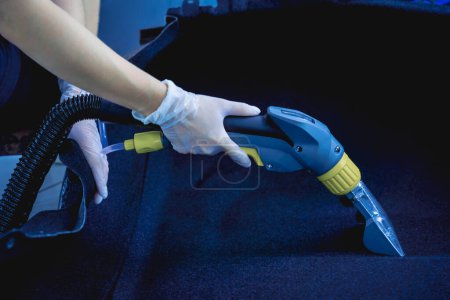 Photo for Young woman cleaning the car details with a washing vacuum cleaner. - Royalty Free Image
