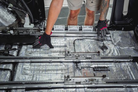Téléchargez les photos : Tunning travailleur de service installer le matériel d'insonorisation à l'intérieur de la voiture intérieure. - en image libre de droit
