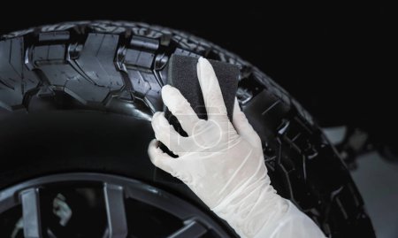 Téléchargez les photos : Pneus de voiture de polissage professionnel de travailleur de service de voiture avec éponge noire. - en image libre de droit
