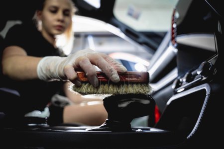 Téléchargez les photos : Jeune femme nettoyage de l'intérieur de la voiture à l'aide d'une brosse spéciale avec mousse. - en image libre de droit