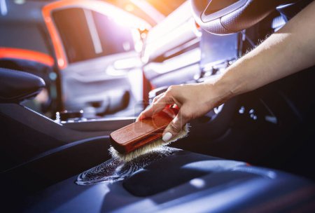 Photo for Young woman cleaning the car interior using a special brush with foam. - Royalty Free Image