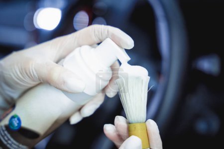 Photo for Young woman cleaning the steering wheel of car using a special brush with foam. - Royalty Free Image