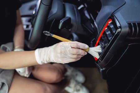 Photo for Young woman cleaning the car interior using a special brush with foam. - Royalty Free Image
