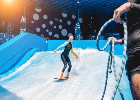 Photo for Beautiful young woman surfing with trainer on a wave simulator at a water amusement park. - Royalty Free Image