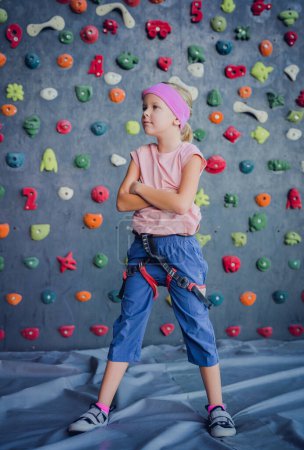 Téléchargez les photos : Un bébé grimpeur fort posant pour photographe au mur artificiel - en image libre de droit