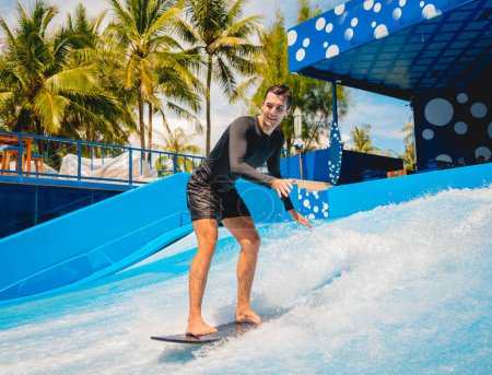 Foto de Joven surfeando en un simulador de olas en un parque de atracciones acuático. - Imagen libre de derechos