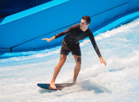 Foto de Joven surfeando en un simulador de olas en un parque de atracciones acuático. - Imagen libre de derechos