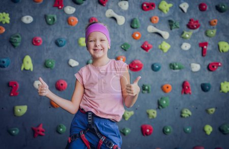 Photo for A strong baby climber posing for photographer at artificial wall - Royalty Free Image